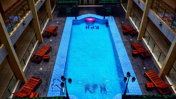 A rooftop swimming pool with multiple levels of seating and a Heineken-branded area. - Regent Palace Hotel (Freetown)