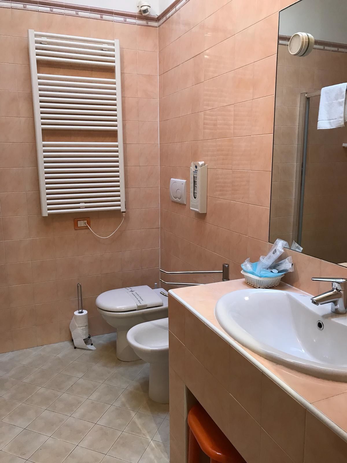 Un baño con inodoro, lavamanos, bidé y un perchero para toallas.