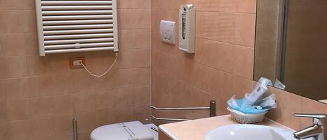 Un baño con inodoro, lavamanos, bidé y un perchero para toallas.