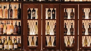 A restaurant interior with a wine rack filled with various bottles, a wooden table with chairs, and a menu on the table. - Abokamento Boutique Rooms (Split)