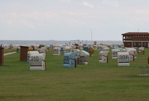 Mailboxes line a serene grassy field, overlooking a tranquil body of water and a distant bridge.