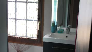 A bathroom with a window, sink, mirror, and towel rack.