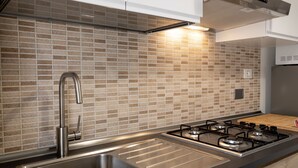 A modern kitchen with a stainless steel sink, a gas stove, and wooden cabinets. - Fornaci 2 - 2-4 people 100 meters from the sea (Pietra Ligure)
