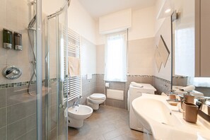Un baño moderno con ducha envuelta en vidrio, inodoro, bidé y una bañera grande.