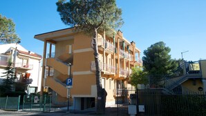A multi-story building with balconies, a parking sign, and a tree in front. - Fornaci 2 - 2-4 people 100 meters from the sea (Pietra Ligure)