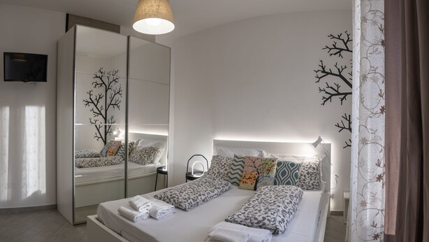 A modern hotel room with a large bed, a mirror, a flat-screen TV, and a bedside table. - Fornaci 2 - 2-4 people 100 meters from the sea (Pietra Ligure)