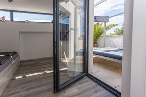 Une chambre moderne dotée d’une porte-fenêtre coulissante donnant sur un espace extérieur aménagé pour se détendre.