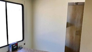 A compact kitchen with a countertop, a window, and a wooden floor.