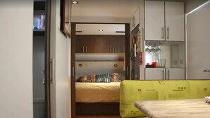A compact bedroom with a bed, a small table, and a wardrobe.