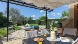 Eine Terrasse im Freien mit einem für das Frühstück gedeckten Tisch, darunter Croissants, Orangensaft und eine Schale Erdbeeren.