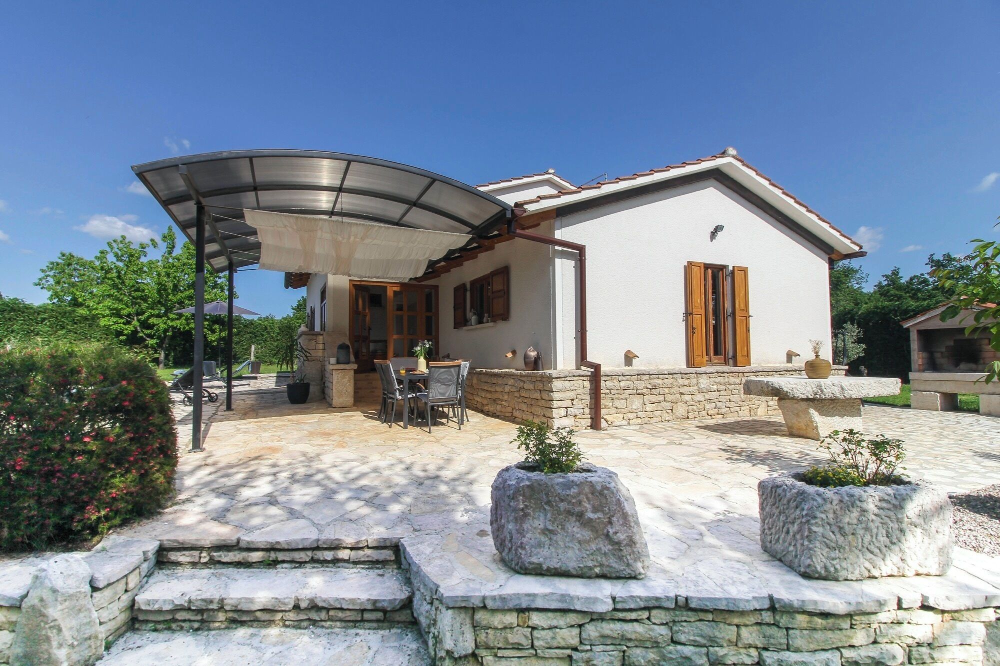 A house with a covered patio, stone steps, and potted plants.