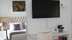 Une chambre à coucher comprenant un lit, un téléviseur fixé au mur, une table de chevet avec une lampe et un petit bureau avec une chaise.