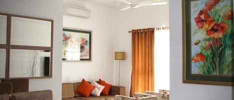 Una sala de estar con sofá, sillones, una mesa de centro, una lámpara de pie y un cuadro en la pared.