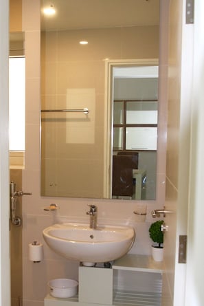 A bathroom with a white sink, a mirror, and a towel rack.