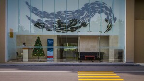 Un bâtiment doté d’une façade en verre, d’un sapin de Noël et d’un banc à l’extérieur.
