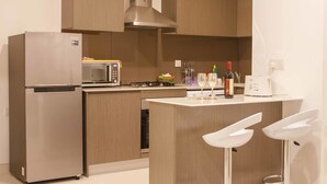 Une cuisine moderne équipée d’un four à micro-ondes encastré, d’un réfrigérateur en acier inoxydable, d’une cuisinière à gaz et d’un petit îlot central avec des tabourets de bar.