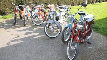 Une rangée de vélos anciens est garée sur un chemin de gravier.