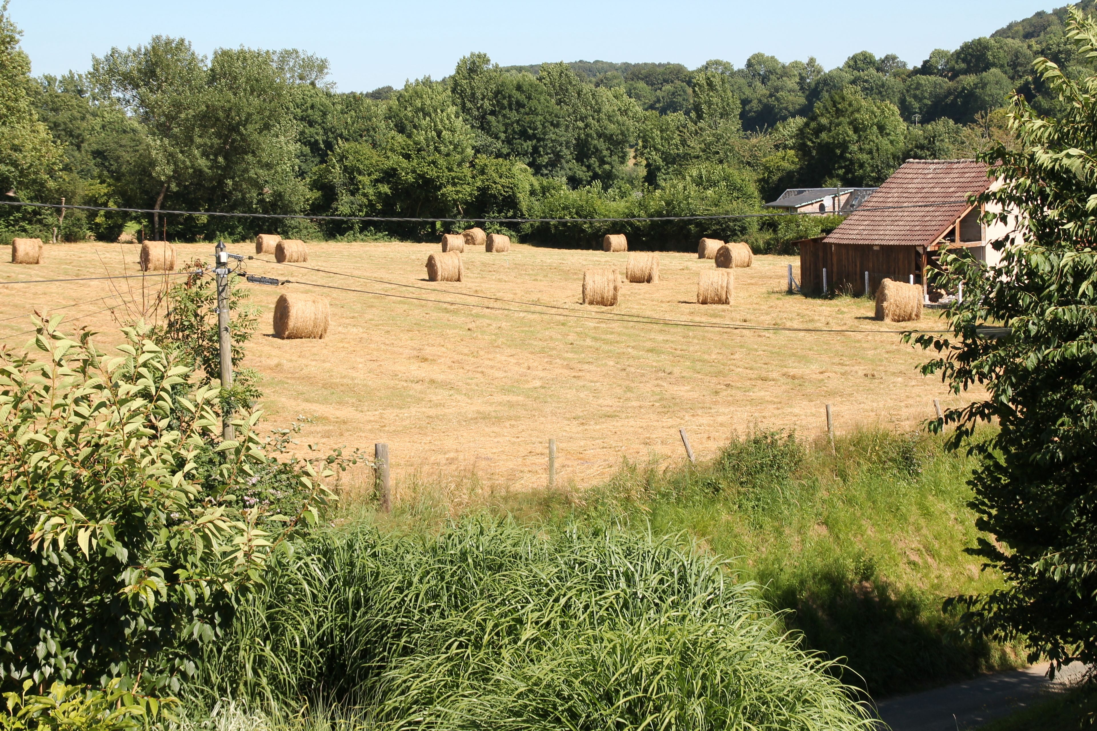 Een landelijk landschap met hooi-balen, een houten gebouw en een omheining.