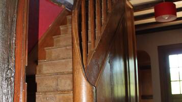 A wooden staircase with a red accent, leading to a room with a tiled floor and a window.