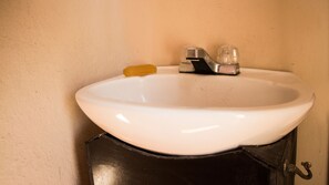 A white sink with a black cabinet, a yellow soap bar, and a faucet. - Hostel & Mezcal (Puebla)