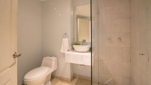 A modern bathroom with a toilet, a sink with a mirror, and a shower area. - 1 BR Beautiful New Apartment in Bocagrande (Cartagena)