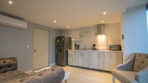 A compact kitchen with a refrigerator, microwave, and coffee maker. There is a sofa and a chair in the living area. - 1 BR Beautiful New Apartment in Bocagrande (Cartagena)
