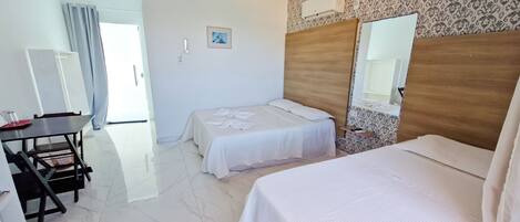 A hotel room with two beds, a desk, and a chair.
