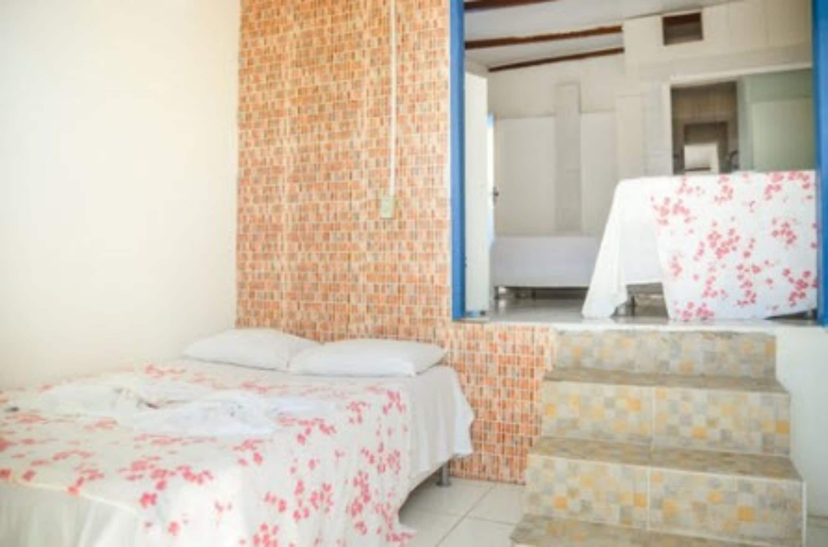 Quarto com cama, banheiro com chuveiro e escada.