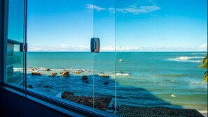Une vue sur l’océan à travers une fenêtre en verre, avec un ciel dégagé.