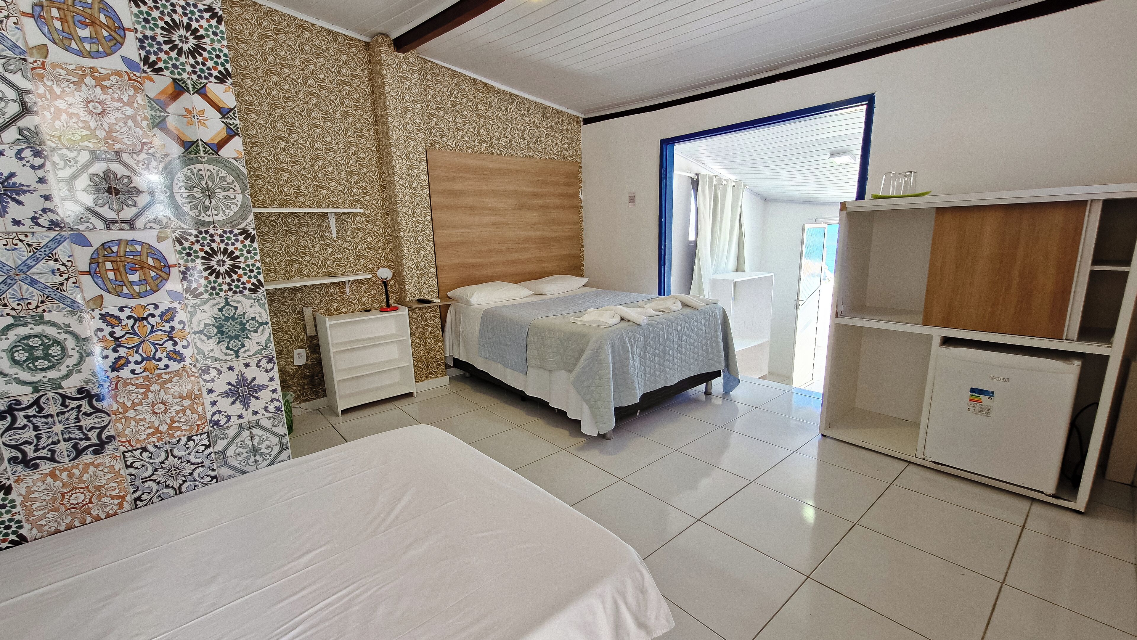 A bedroom with a bed, a nightstand, a wardrobe, and a patterned wall.