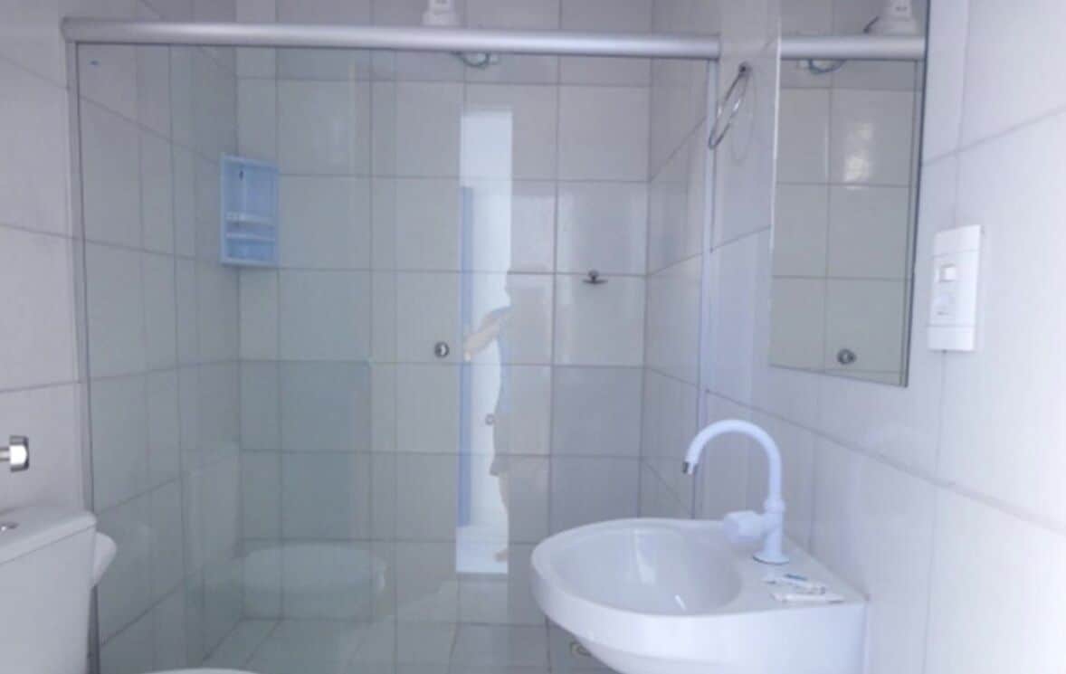 A bathroom with a glass-enclosed shower, a sink, and a mirror.