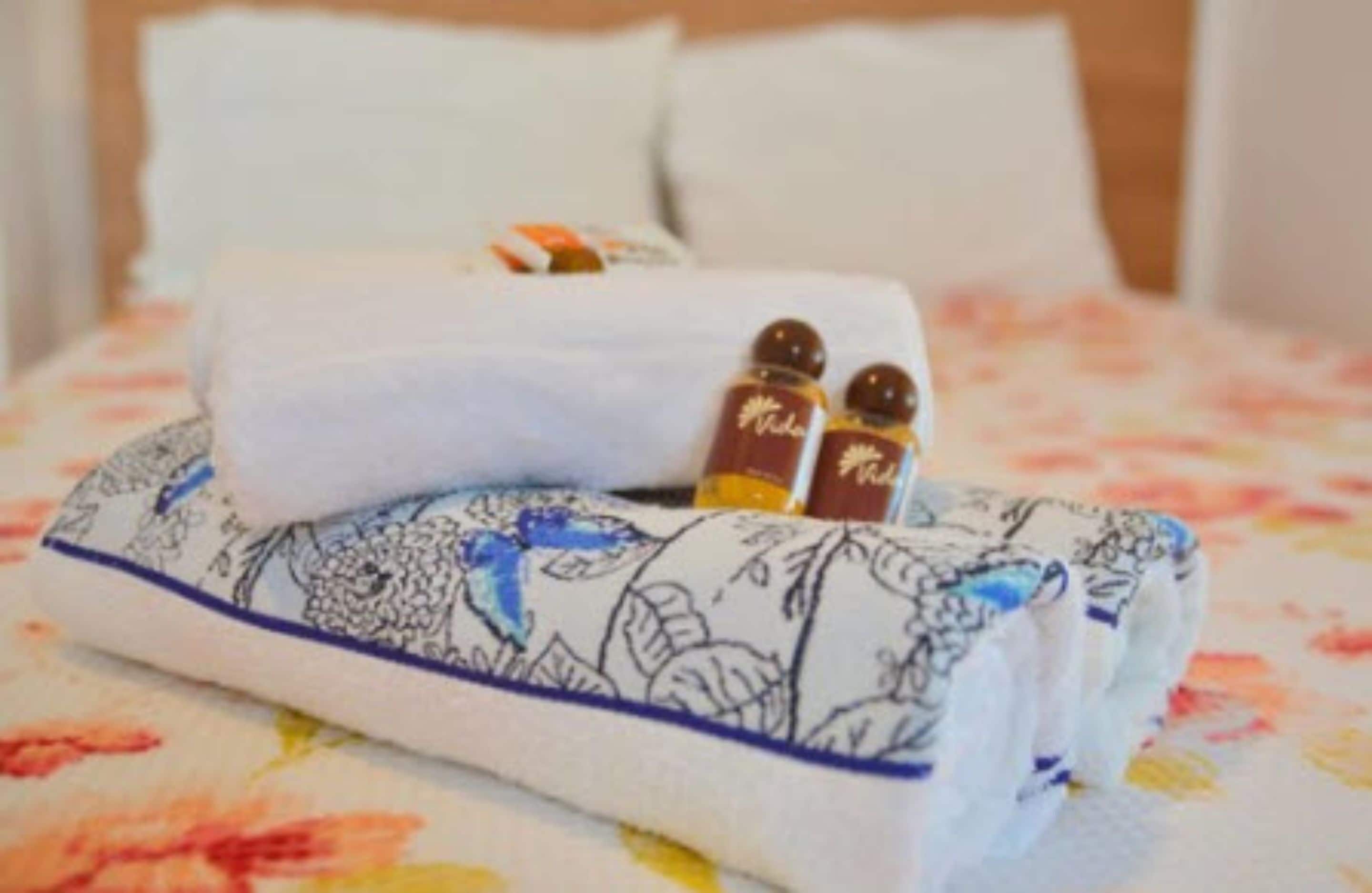A neatly made bed with a floral-patterned bedspread and a folded towel.