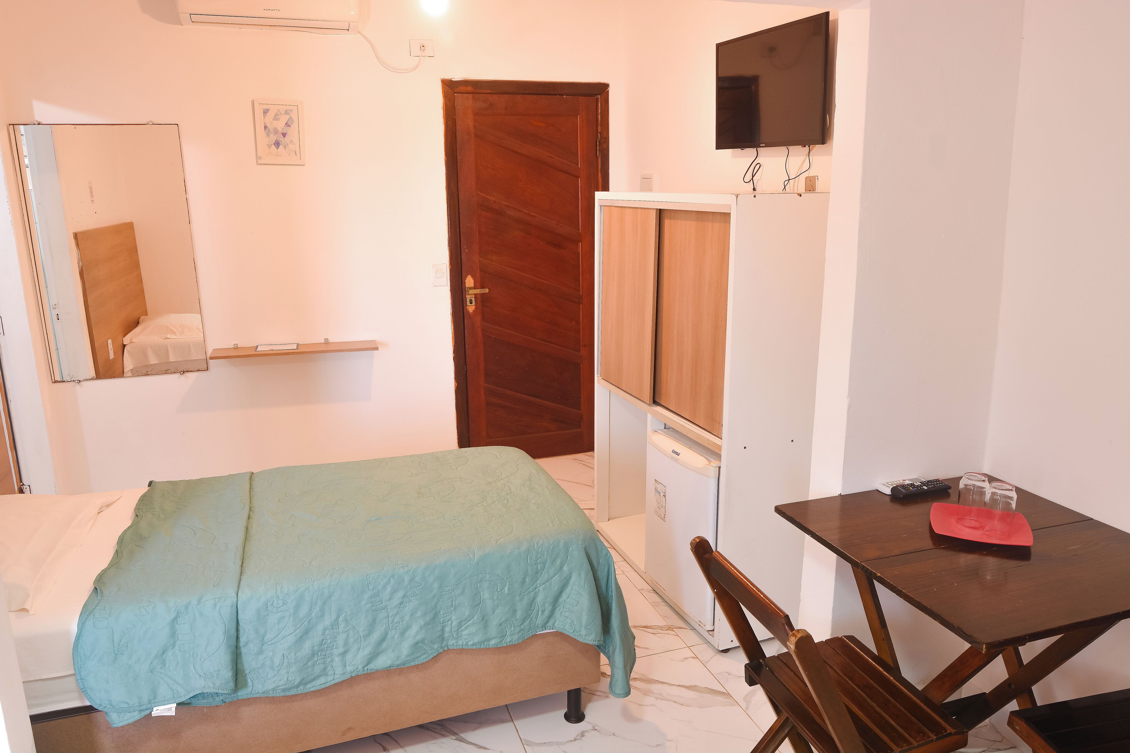 Ein Schlafzimmer mit Bett, Schreibtisch, Stuhl, Kleiderschrank und Fernseher.