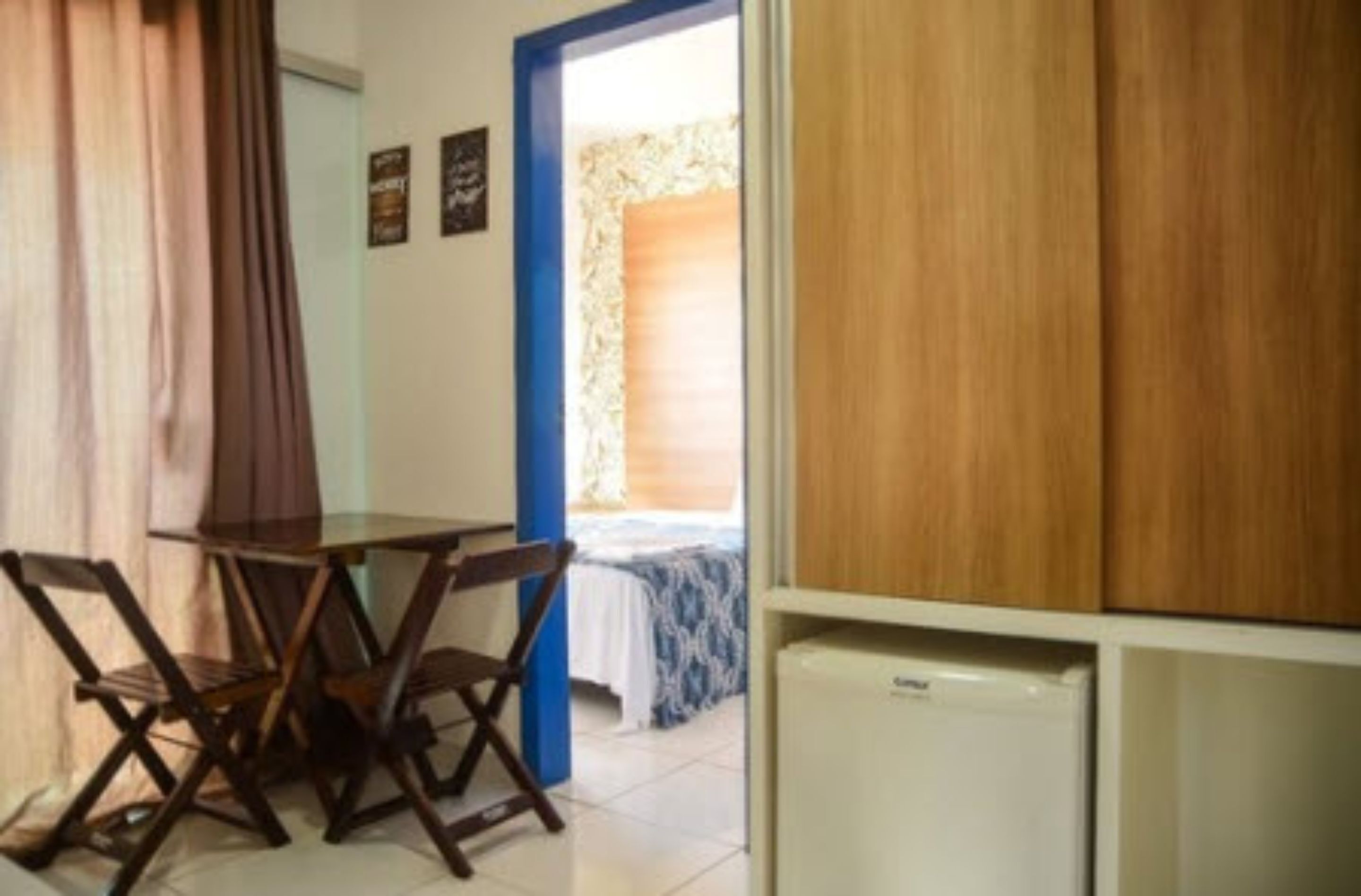 Una stanza con un letto, un tavolino e un frigorifero.