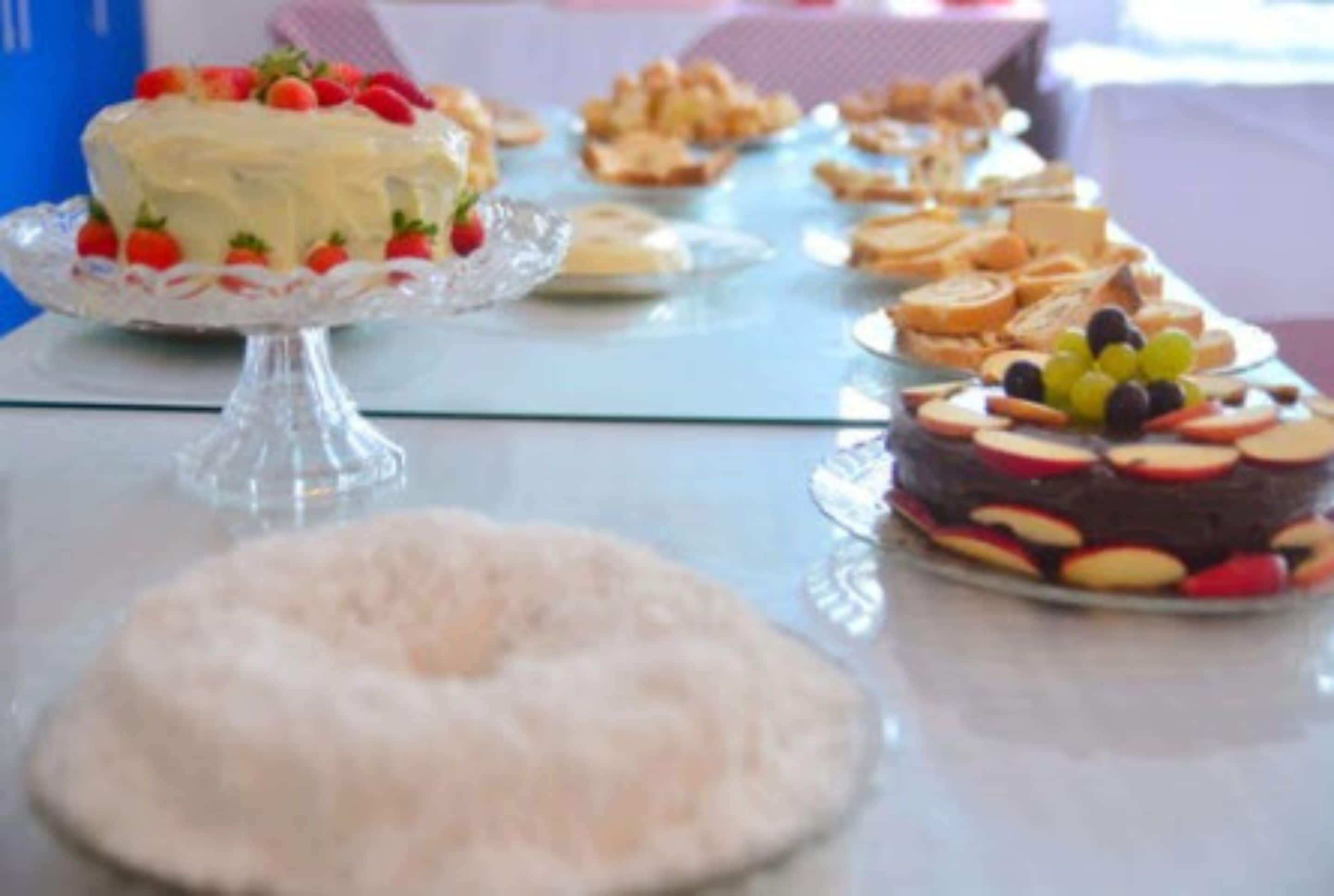 A buffet table with various desserts including cakes and fruit arrangements.