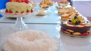 Una mesa de buffet con diversos postres, incluyendo pasteles y arreglos de frutas.