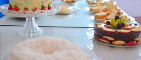 Una mesa de buffet con diversos postres, incluyendo pasteles y arreglos de frutas.