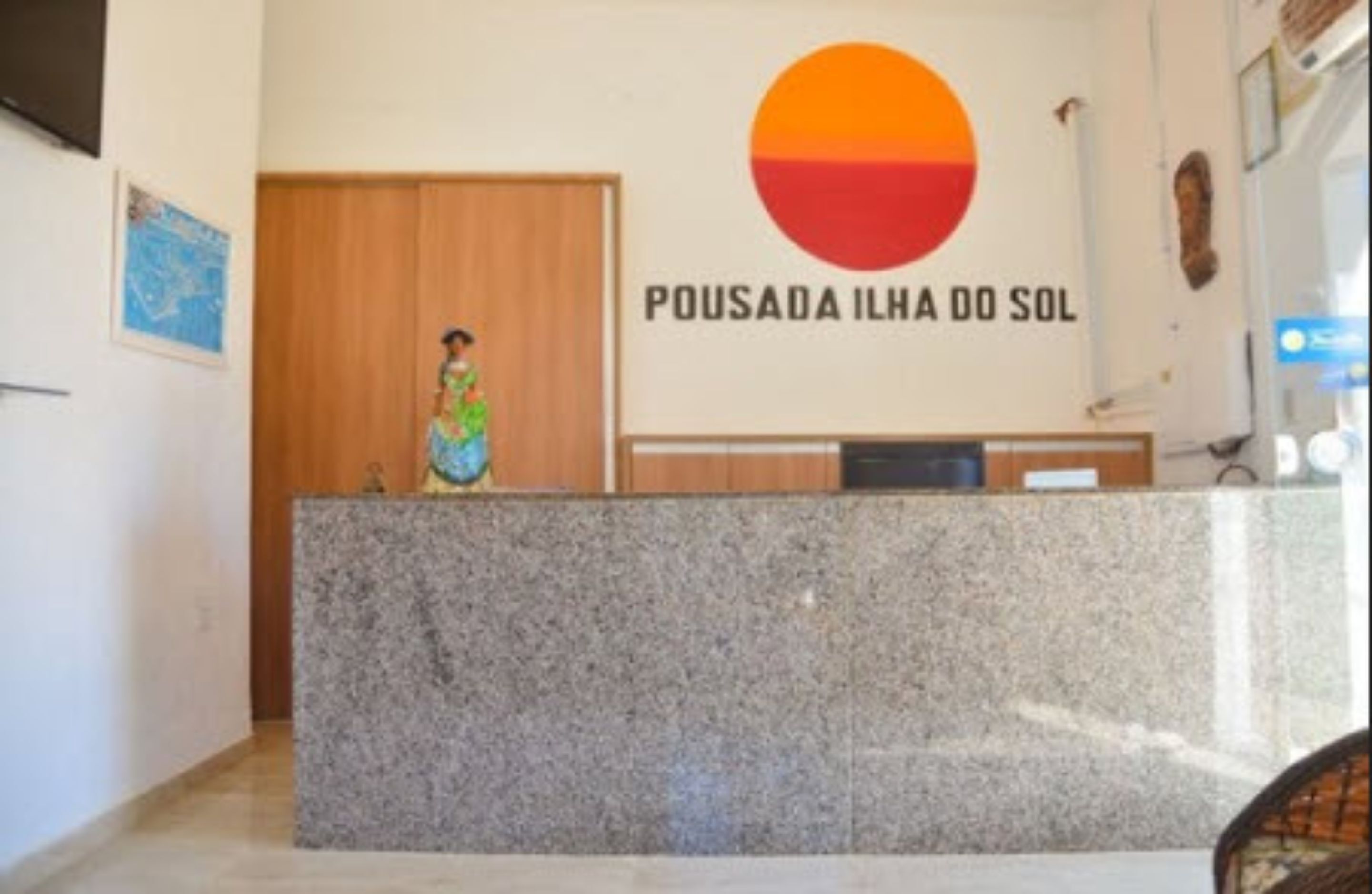 Un comptoir d’accueil avec une pancarte indiquant « POUSADA ILHA DO SOL » et une femme se tenant derrière.