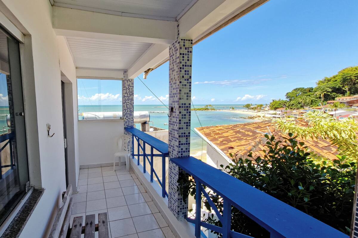 A balcony with a view of the sea and a tiled roof.
