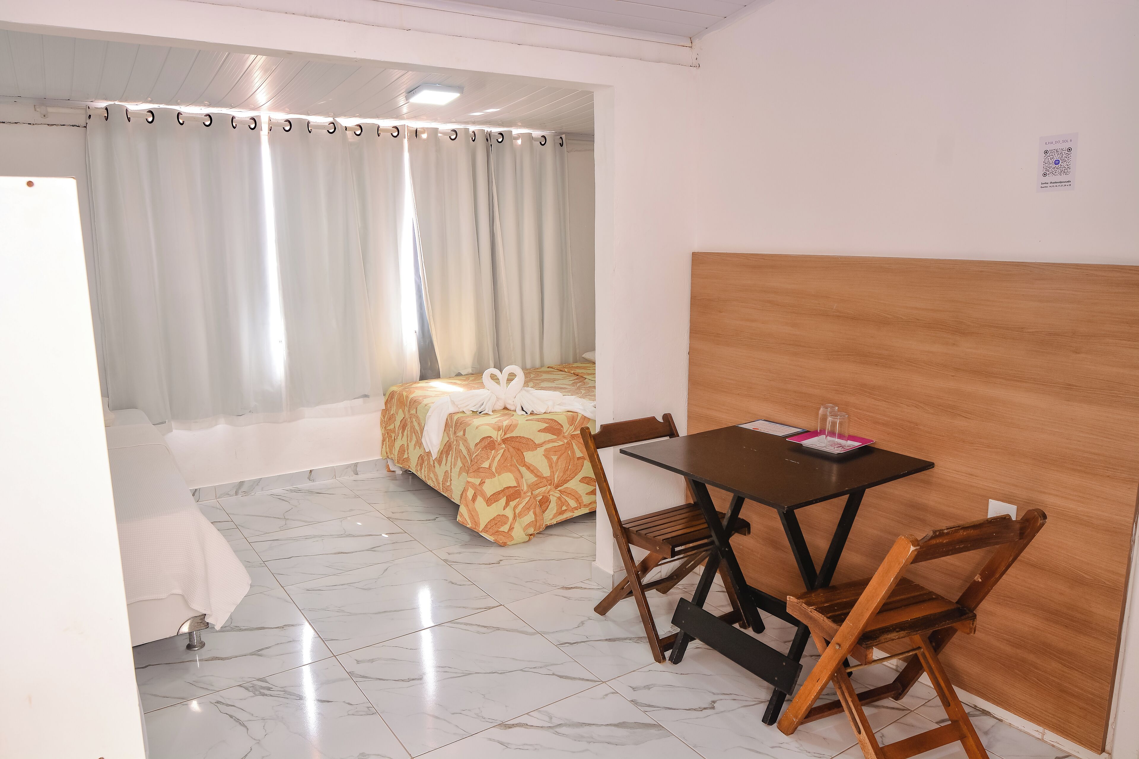 Ein Hotelzimmer mit Bett, Esstisch und Stühlen sowie einer Trennwand aus Holz.