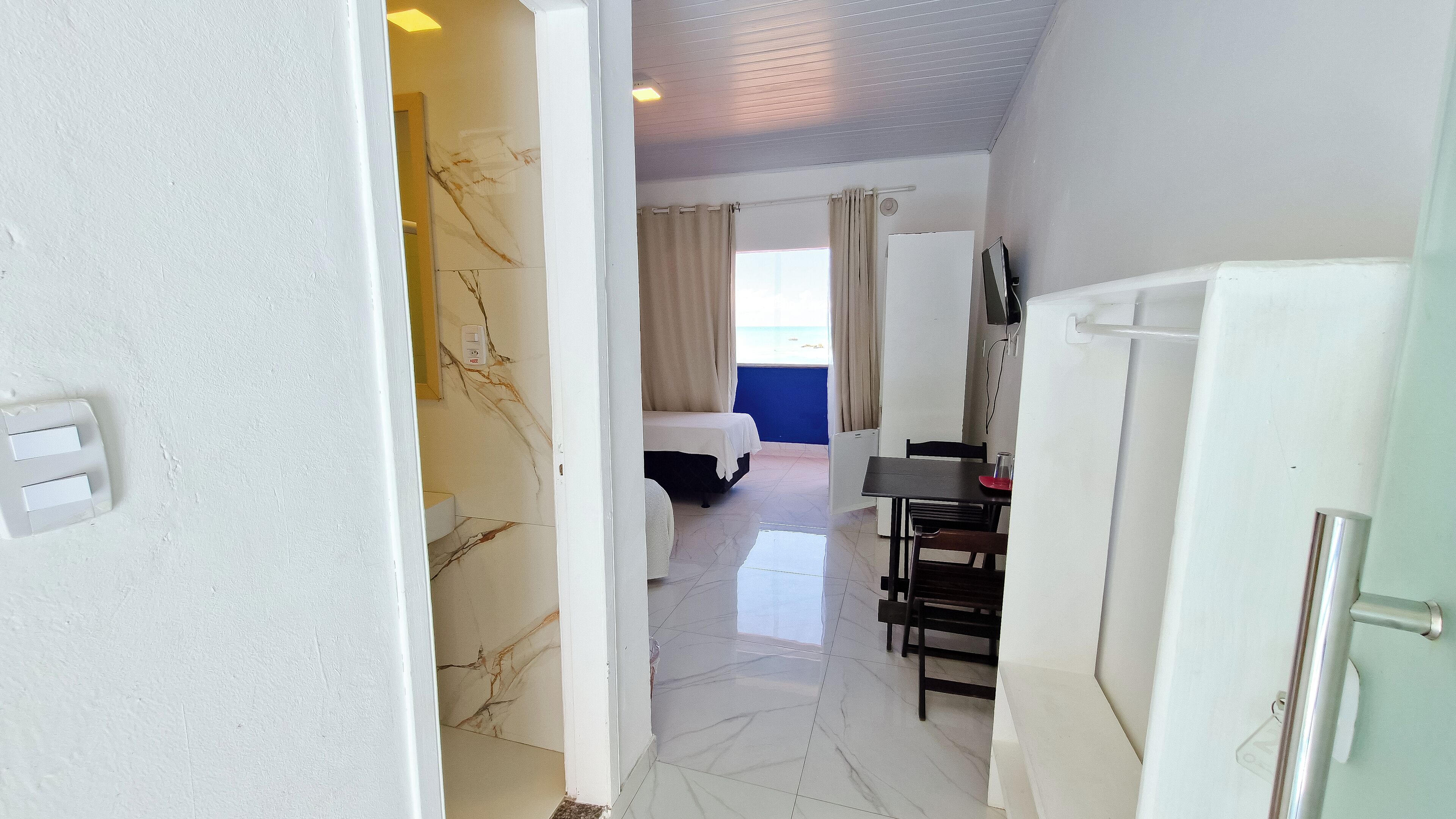 Een hotelkamer met een bed, een bureau, een stoel, een tafel en een koelkast.