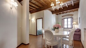 Un comedor con una mesa redonda, sillas blancas y una araña.