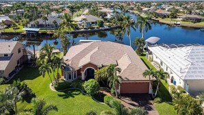 A residential area with houses, a canal, and palm trees.