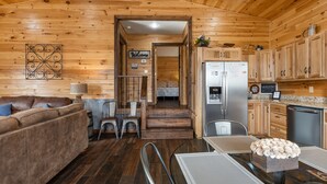 Un accogliente interno di una baita con zona living, angolo pranzo e cucina.