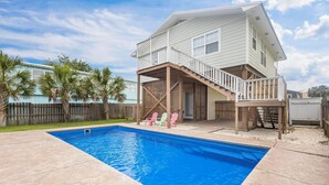 A two-story house with a swimming pool, a covered patio, and a wooden deck.