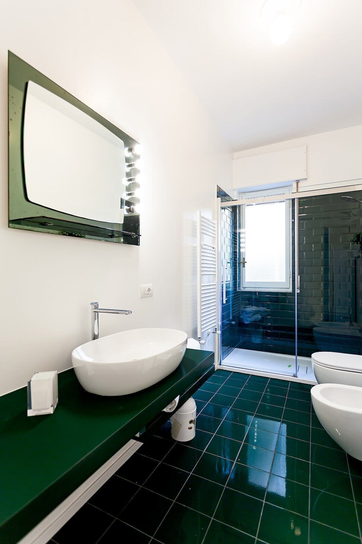 A modern bathroom with a large mirror, a white sink, and a separate toilet.