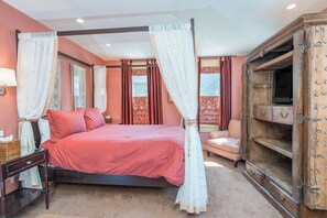 A four-poster bed with a canopy, a wooden cabinet with drawers, and a small bedside table.