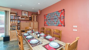 Un espace repas avec une longue table en bois dressée pour un repas, entourée de chaises en bois.