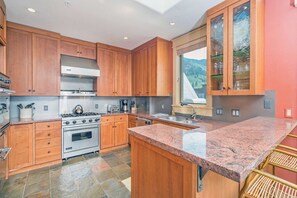 A kitchen with wooden cabinets, a granite countertop, and a large window.
