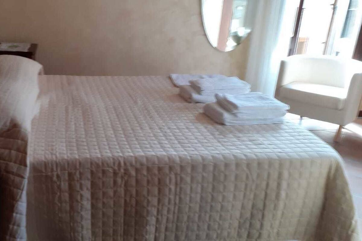 A hotel room with a bed, a nightstand, a chair, and a window.
